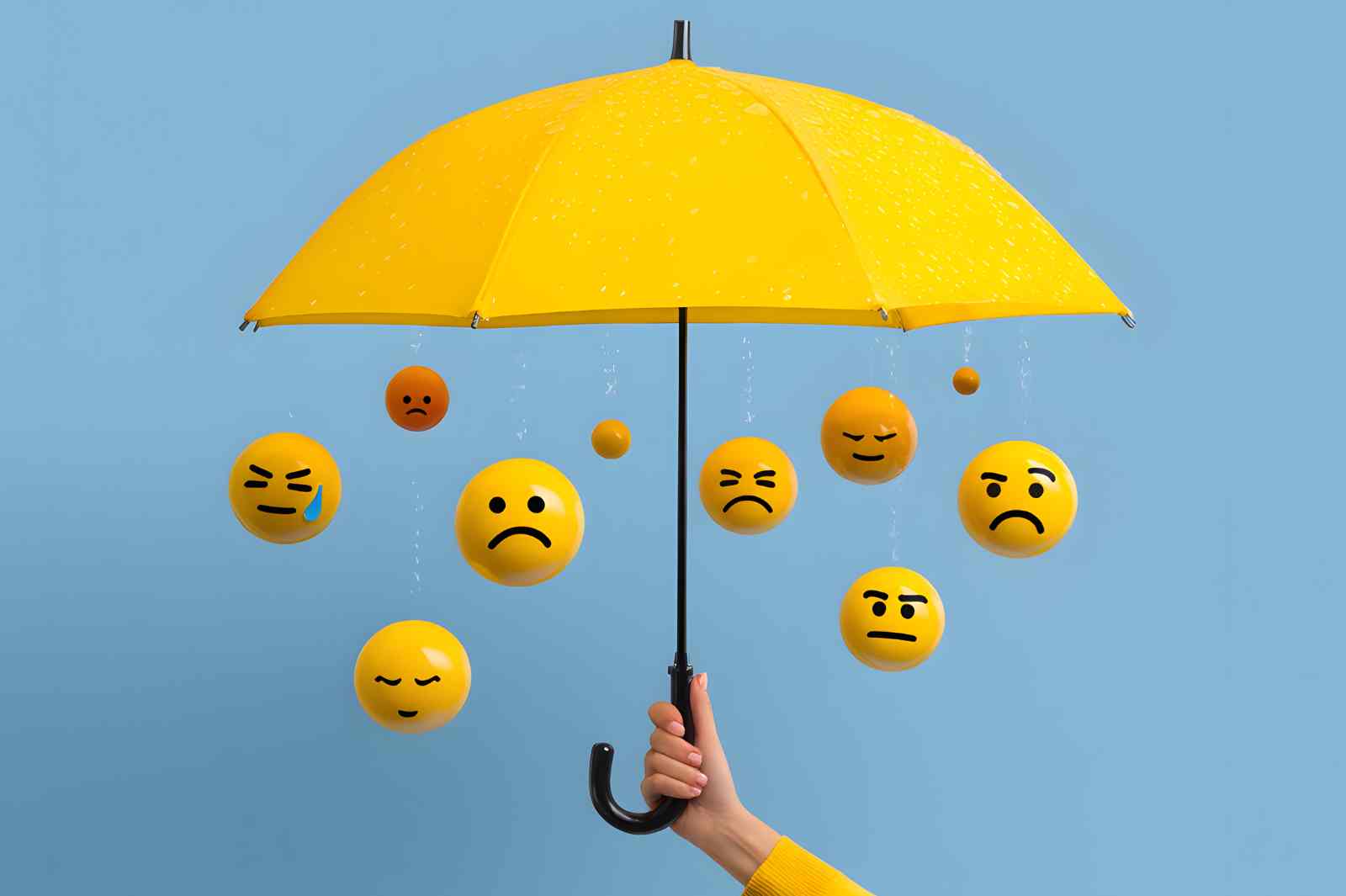 A yellow umbrella shelters a group of sad yellow emoji spheres from the rain.