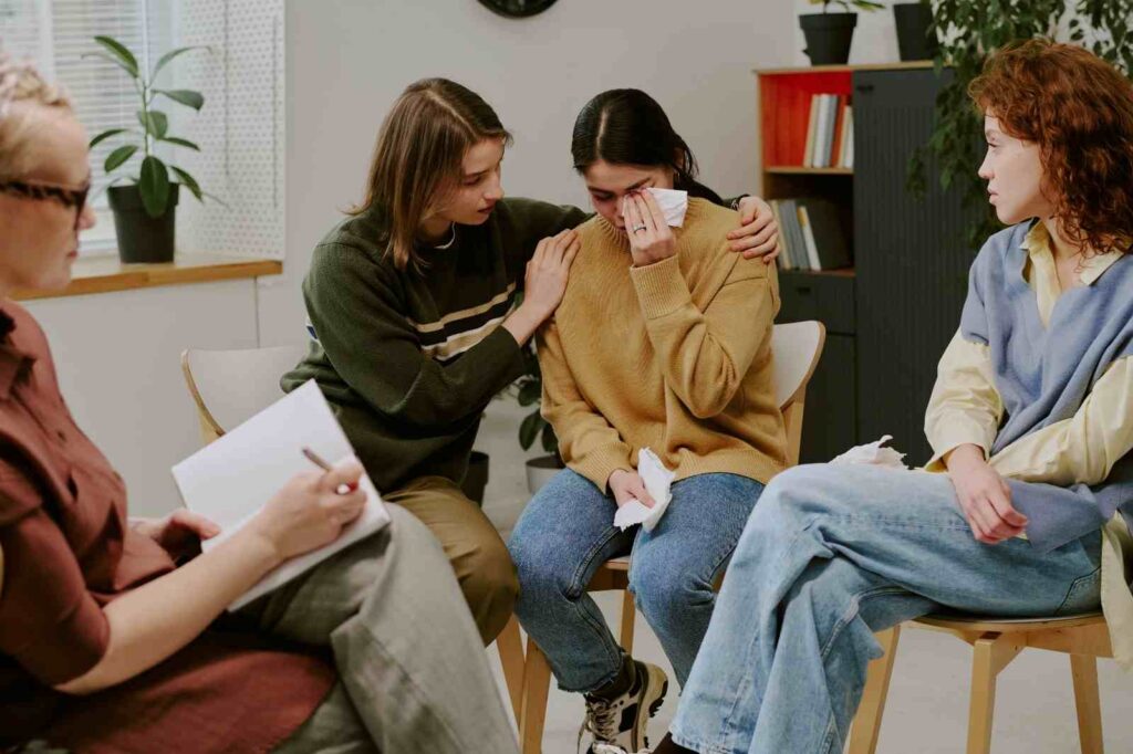 Support group members comforting a crying woman during session