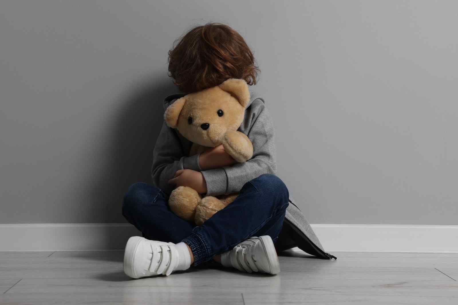 Child holding teddy bear after emotional trauma