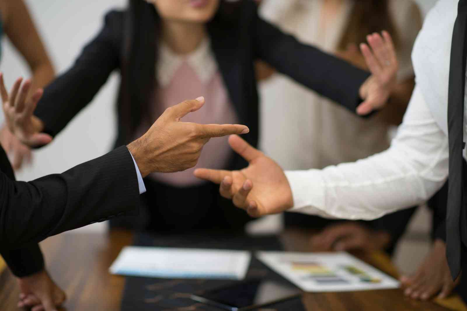 People arguing at a meeting while others try to calm them