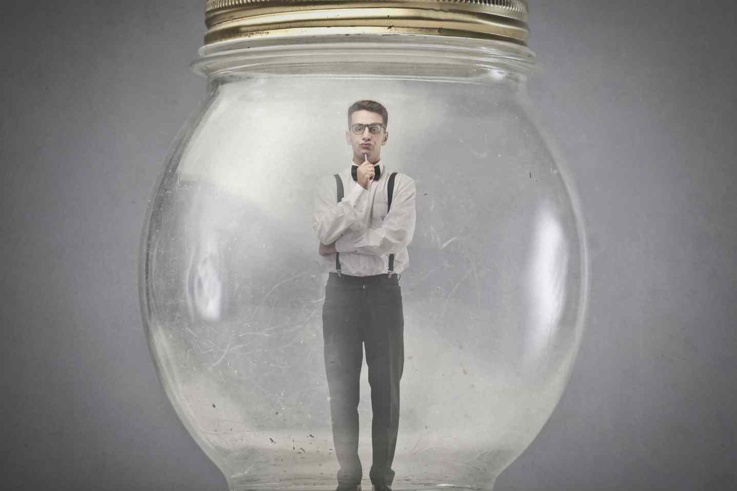 Man standing inside glass jar symbolizing confinement or isolation