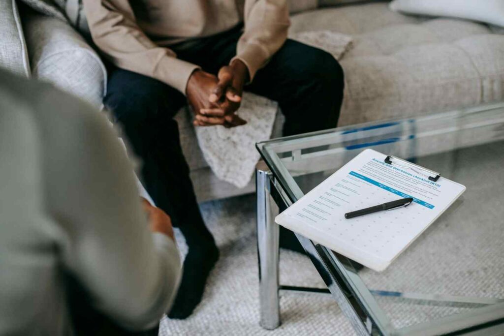Clipboard with form on table during counseling session with seated person.