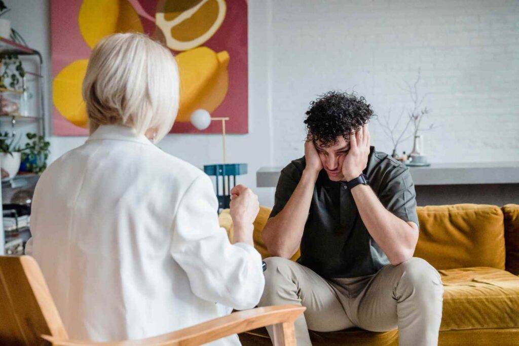 Person holding head while talking to therapist in a counseling session.