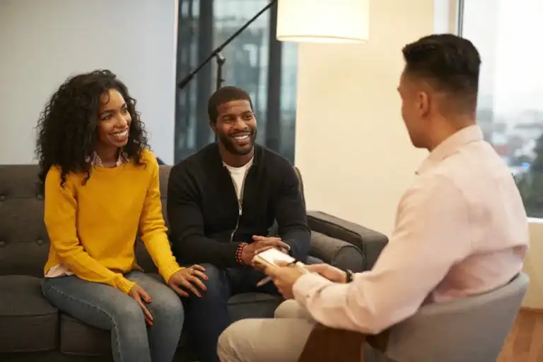 Smiling couple sitting together talking to their relationship counselor