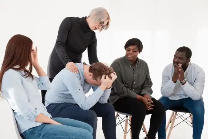 People supporting a man in distress during group therapy