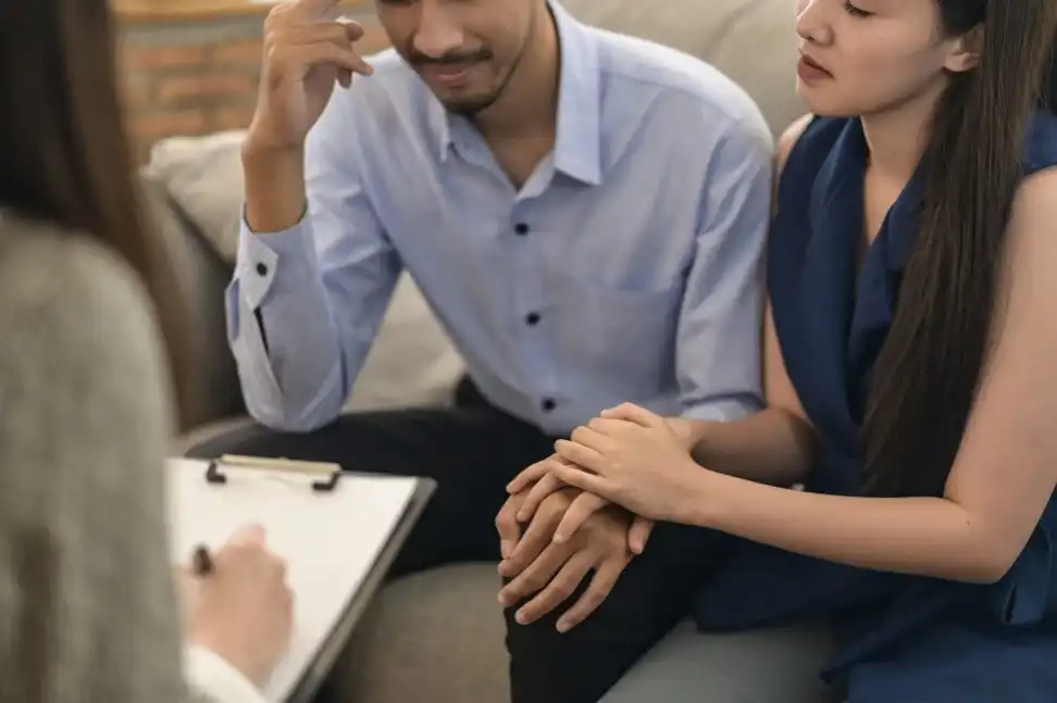 Couple sitting on a sofa talking to a marriage counselor